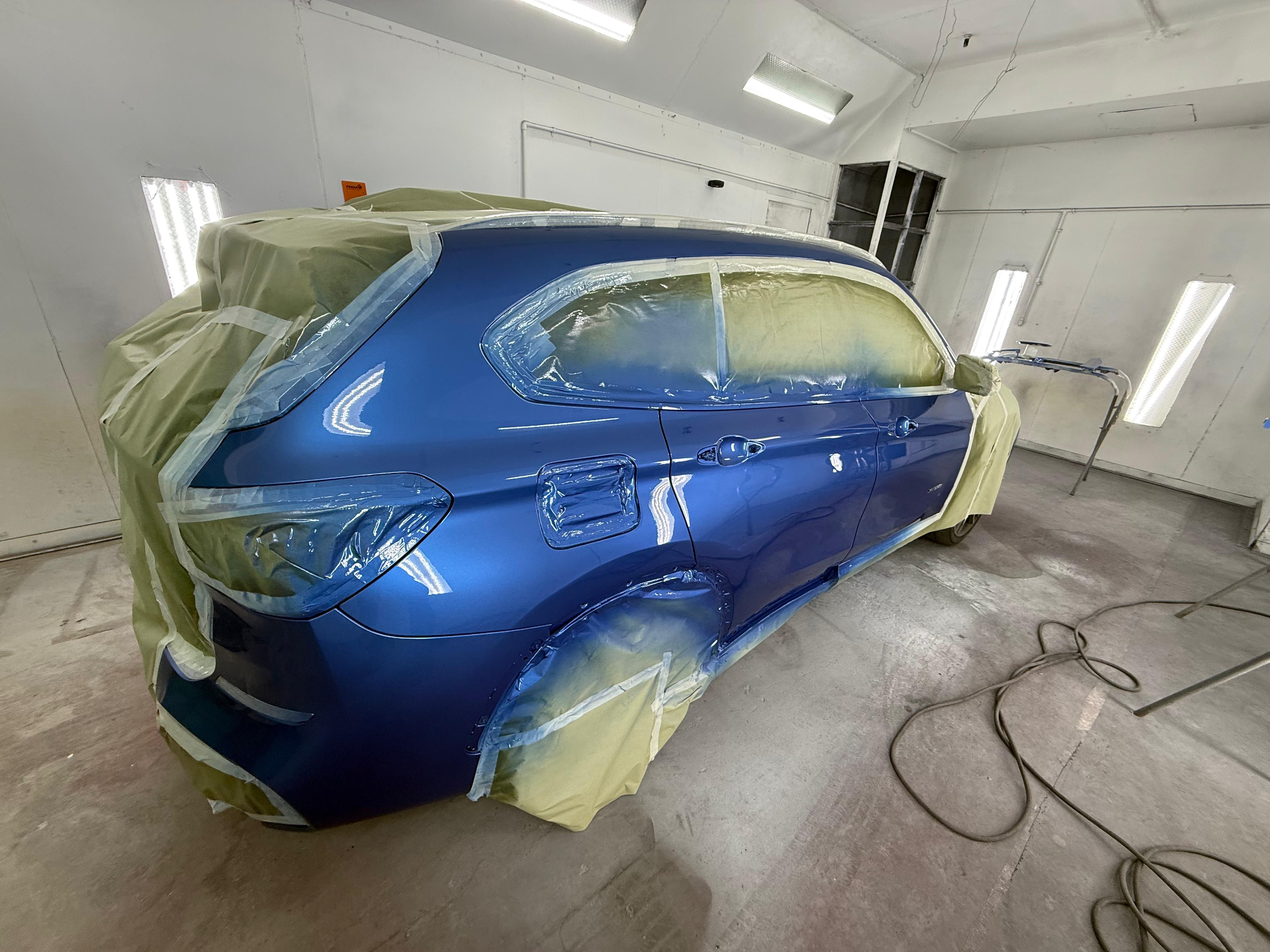 Blue SUV rear quarter custom paint in booth